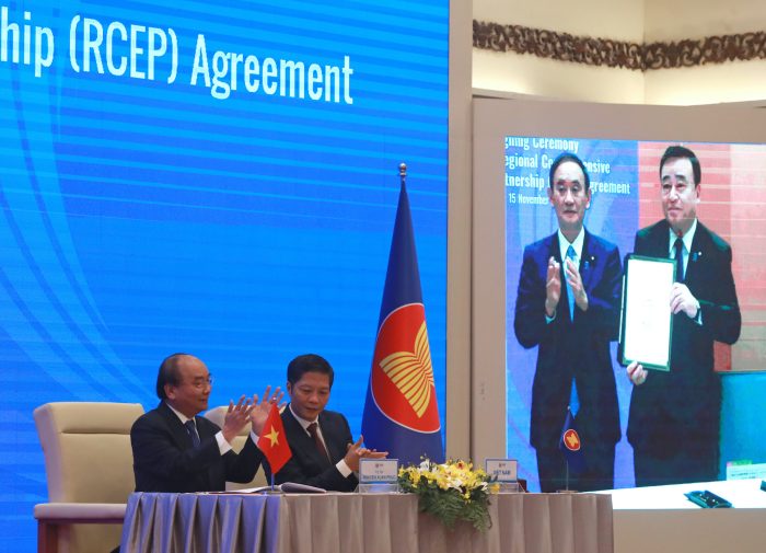 ///Vietnamese Prime Minister Nguyen Xuan Phuc (L) and Minister of Trade Tran Tuan Anh (R) applaud next to a screen showing Japanese Prime Minister Yoshihide Suga and Minister of Trade Kajiyama Hiroshi holding up signed RCEP agreement. China and 14 other countries have agreed to set up the world’s largest trading bloc, encompassing nearly a third of all economic activity, in a deal many in Asia are hoping will help hasten a recovery from the shocks of the pandemic. (AP Photo/Hau Dinh)