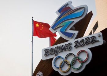 The Chinese national flag flies behind the logo of the Beijing 2022 Winter Olympics in Beijing, China, January 14, 2022. REUTERS/Thomas Peter