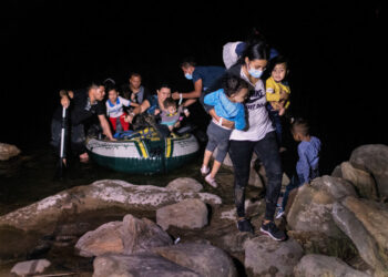 ROMA, TEXAS - APRIL 30: An immigrant mother carries her children up the bank of the Rio Grande after crossing the U.S.-Mexico border early on April 30, 2021 in Roma, Texas. A surge of mostly Central American immigrants crossing into the United States has challenged U.S. immigration agencies along the U.S. southern border. (Photo by John Moore/Getty Images)