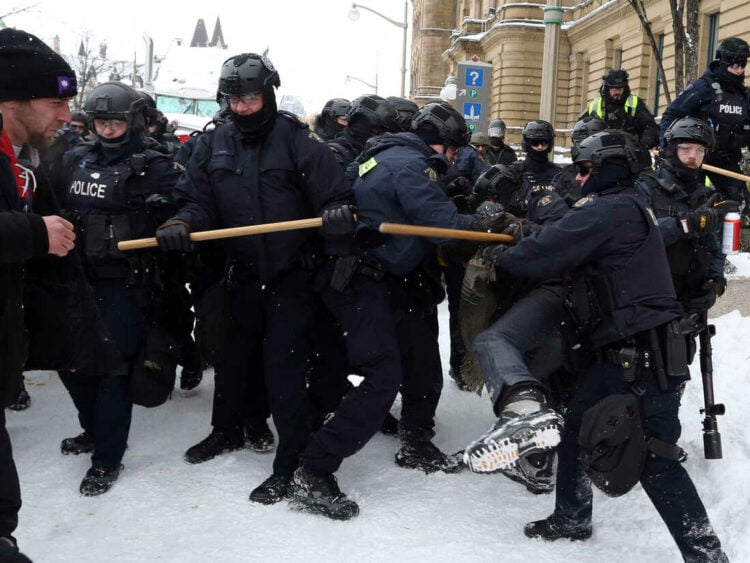 A demonstrator (R) is detained by police as they push protesters back on February 19, 2022 in Ottawa, Canada. - Police in Canada deployed to dislodge the final truckers and protesters from downtown Ottawa, aimed at bringing an end to three weeks of demonstrations over Covid-19 health rules. Ottawa police, who pledged the operation would push ahead "until residents and citizens have their city back," were still working to clear the capital's streets. (Photo by Dave Chan / AFP) (Photo by DAVE CHAN/AFP via Getty Images)