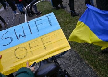 A demonstrator holds a placard reading "SWIFT OFF", refering to the international SWIFT financial transfer networkduring a protest against Russia's invasion of the Ukraine on February 25, 2022 in front of the Chancellery  in Berlin. (Photo by John MACDOUGALL / AFP) (Photo by JOHN MACDOUGALL/AFP via Getty Images)