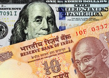 An orange Indian ten rupee bank note, close up, with an American one hundred dollar bill