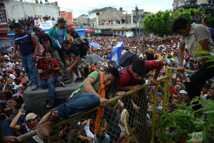 Thousands of Central American migrants rush across the border towards Mexico, in Tecun Uman, Guatemala, Friday, Oct. 19, 2018, as part of a second migrant caravan. After arriving at the tall, yellow metal fence some clambered atop it and on U.S.-donated military jeeps, as young men began violently tugging on the barrier and finally succeeded in tearing it down. (AP Photo/Oliver de Ros)
