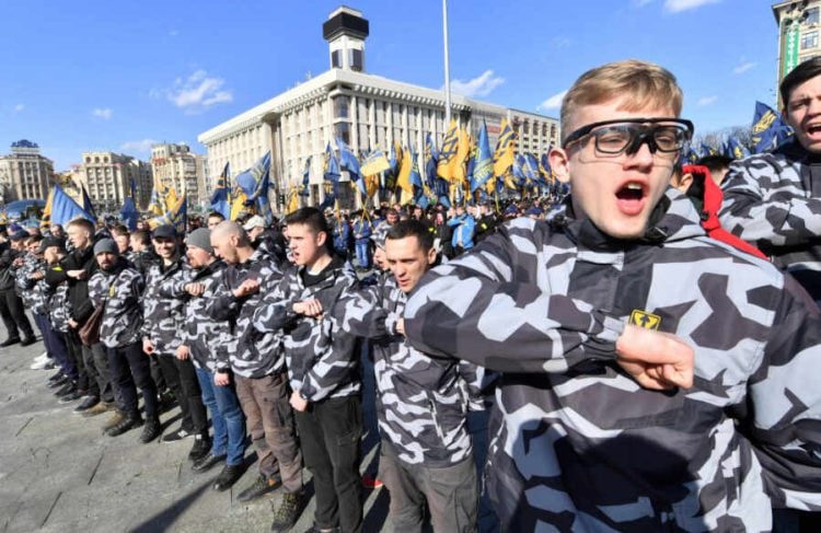 Activists of the Ukrainian far-right party National Corps salute during their rally at the Independence Square in Kiev, on March 9, 2019. - The protesters are demanding strict punishment for Ukraine's President Petro Poroshenko's allies, who they accuse of profiting from the sale of smuggled Russian military parts to state defence companies at inflated prices. Accusations of self-enrichment at the expense of the army are particularly damaging in Ukraine, which has been fighting Russian-backed separatists in the east since 2014. (Photo by Sergei SUPINSKY / AFP)
