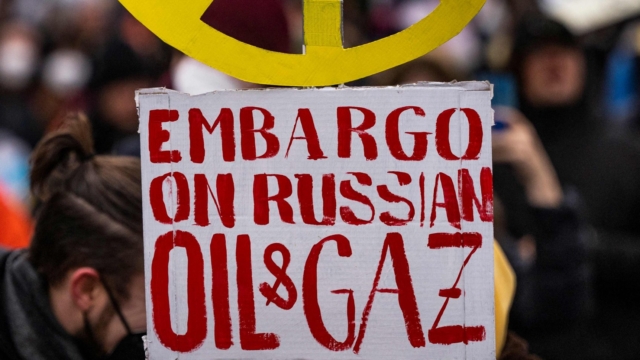 An anti-war protester displays a placard shaped like a peace sign, calling for an embargo on Russian oil and gas at a rally organised by the International Literature festival "For your and for our Freedom! Voices on the War in Ukraine" in Berlin, on March 6, 2022. (Photo by John MACDOUGALL / AFP) (Photo by JOHN MACDOUGALL/AFP via Getty Images)