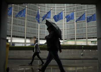 People shelter against the rain as they walk past the EU headquarters in Brussels, Wednesday, Oct. 16, 2019. European Union and British negotiators have failed to get a breakthrough in the Brexit talks during a frantic all-night session and will continue seeking a compromise on the eve of Thursday's crucial EU summit. (AP Photo/Francisco Seco)
