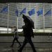 People shelter against the rain as they walk past the EU headquarters in Brussels, Wednesday, Oct. 16, 2019. European Union and British negotiators have failed to get a breakthrough in the Brexit talks during a frantic all-night session and will continue seeking a compromise on the eve of Thursday's crucial EU summit. (AP Photo/Francisco Seco)