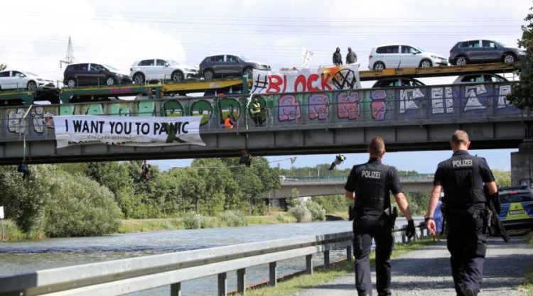 Environmentalists block the rails and stop a train loaded with new Volkswagen cars that has left the Volkswagen (VW) plant in Wolfsburg, northern Germany, on August 13, 2019. - The activists of the group "Aktion Autofrei" (action car free) call for the expansion of climate-friendly public transport. (Photo by Bodo Marks / dpa / AFP) / Germany OUT        (Photo credit should read BODO MARKS/DPA/AFP via Getty Images)