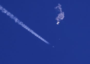 In this photo provided by Chad Fish, the remnants of a large balloon drift above the Atlantic Ocean, just off the coast of South Carolina, with a fighter jet and its contrail seen below it, Saturday, Feb. 4, 2023. The downing of the suspected Chinese spy balloon by a missile from an F-22 fighter jet created a spectacle over one of the state’s tourism hubs and drew crowds reacting with a mixture of bewildered gazing, distress and cheering. (Chad Fish via AP)