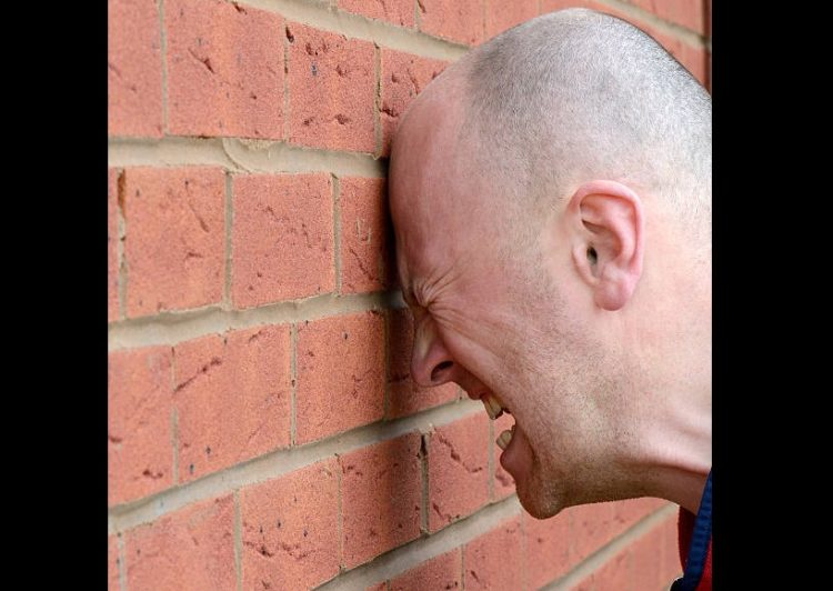 a man banging his head agaist the wall in frustration