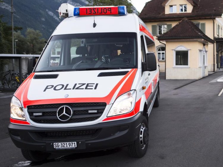In this Aug. 13, 2016 picture  a police car stands   at the train station following an attack onboard, in Salez, Switzerland.  A 34-year-old woman died Sunday from wounds suffered after a man attacked her and four others with a knife and a burning liquid aboard a crowded train in Switzerland. Police are still searching for a motive but said there's no indication the suspect, identified only as a 27-year-old Swiss man from a neighboring region, had ties to extremist groups. (Gian Ehrenzeller/Keystone via AP)