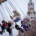 Children and their parents ride a carousel at a Christmas Market set up in Red Square decorated for the New Year and Christmas festivities with the Spasskaya Tower in the background in Moscow, Russia, Sunday, Dec. 17, 2023. (AP Photo/Alexander Zemlianichenko)