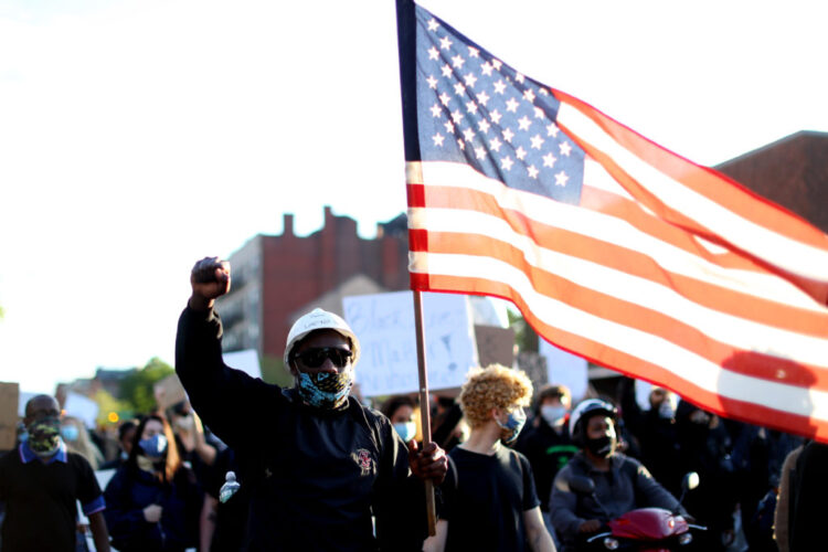 BOSTON, MASSACHUSETTS - MAY 31: A protester waves a flag during a demonstration in response to the recent death of George Floyd on May 31, 2020 in Boston, Massachusetts. Protests spread across cities in the U.S., and in other parts of the world in response to the death of African American George Floyd while in police custody in Minneapolis, Minnesota. (Photo by Maddie Meyer/Getty Images)