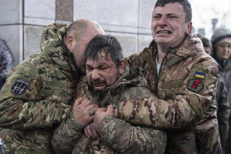 Ukrainian servicemen cry near the coffin of their comrade Andrii Trachuk during his funeral service on Independence square in Kyiv, Ukraine, Friday, Dec. 15, 2023. Trachuk was a veteran of Revolution of Dignity and was killed by Russian forces on Dec. 9, 2023 near Kherson. (AP Photo/Evgeniy Maloletka)